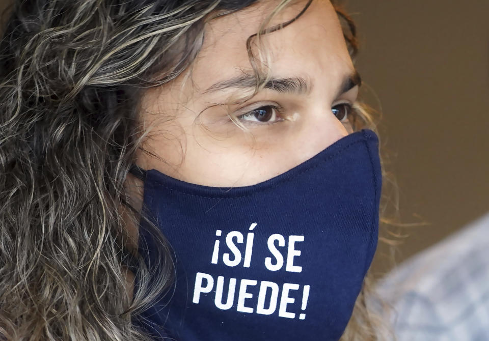 Stephanie Lopez-Burgus, wearing a mask with the slogan, in Spanish, "Yes We Can," prepares to canvas a neighborhood for the Working Families Party about the U.S. Senate races, Wednesday, Dec. 16, 2020, in Lawrenceville, Ga. (AP Photo/Tami Chappell)