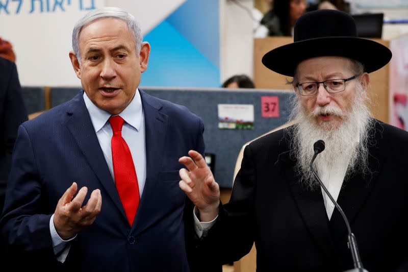 FILE PHOTO: Israeli Prime Minister Benjamin Netanyahu and Health Minister Yaakov Litzman gesture as they deliver statements during a visit to the Health Ministry national hotline, in Kiryat Malachi, Israel