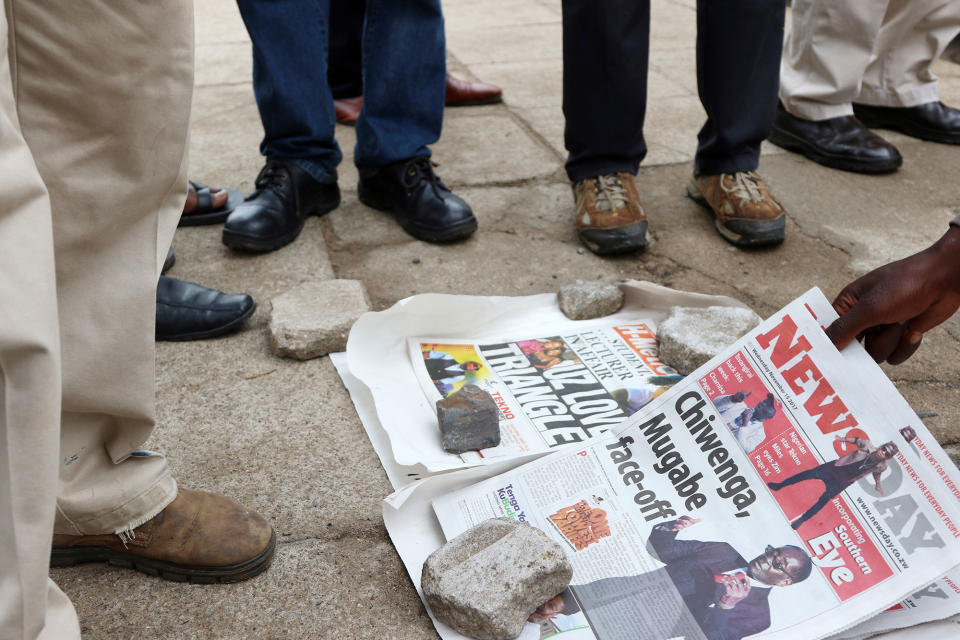 <p>Zimbabweans check newspapers as armed soldiers patrol the streets in Harare, Wednesday, Nov. 15, 2017. (Photo: AP) </p>