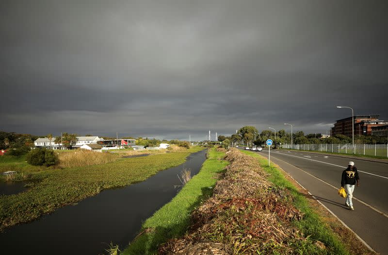 A man walks past contested land earmarked for a development which includes a new Africa headquarters for U.S. retail giant Amazon in Cape Town