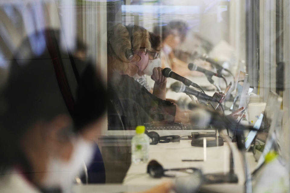 Interpreters work at the main press center during the 2020 Summer Olympics, Friday, July 30, 2021, in Tokyo, Japan. Unlike previous Olympics, all the interpretation is being done remotely with most interpreters working in booths at the main center. About two dozens interpreters aren't even in the country, chiming in from the Americas or Europe to handle late night events in Japan. (AP Photo/Luca Bruno)