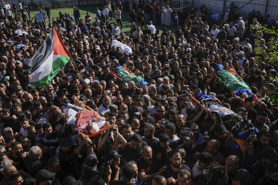 Mourners carry the bodies of Palestinians, some are draped in the Hamas and Islamic Jihad militant group flags during their funeral in the Nur Shams refugee camp, near the West Bank town of Tulkarem, Sunday, April 21, 2024. The Palestinian Red Crescent rescue service said 14 bodies have been recovered from the Nur Shams urban refugee camp since an Israeli military operation began in the area Thursday night. The Islamic Jihad militant group confirmed the deaths of three members. Another killed was a 15-year-old boy. The Israeli army said its forces killed 10 militants in the camp and surrounding areas while eight suspects were arrested. (AP Photo/Majdi Mohammed)