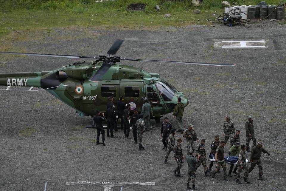 Indian army soldiers carry a body of a cloudburst victim, at Baltal, 105 kilometers (65miles) northeast of Srinagar, Indian controlled Kashmir, Saturday, July 9, 2022. At least eight pilgrims have been killed after a cloudburst triggered a flash flooding during an annual Hindu pilgrimage to an icy Himalayan cave in Indian-controlled Kashmir. Officials say the cloudburst near the hollowed mountain cave revered by Hindus on Friday sent a wall of water down a mountain gorge and swept about two dozen encampments and two makeshift kitchens. (AP Photo/Mukhtar Khan)