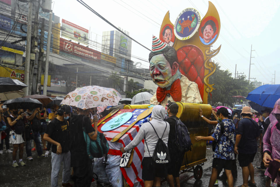 Protesters push and position the effigy of Philippine President Ferdinand Marcos in the rain during a rally against the State of the Nation address in Quezon City, Philippines Monday, July 25, 2022. Philippine President Ferdinand Marcos Jr. will deliver his first State of the Nation address Monday with momentum from his landslide election victory, but he's hamstrung by history as an ousted dictator’s son and daunting economic headwinds. (AP Photo/Gerard Carreon)