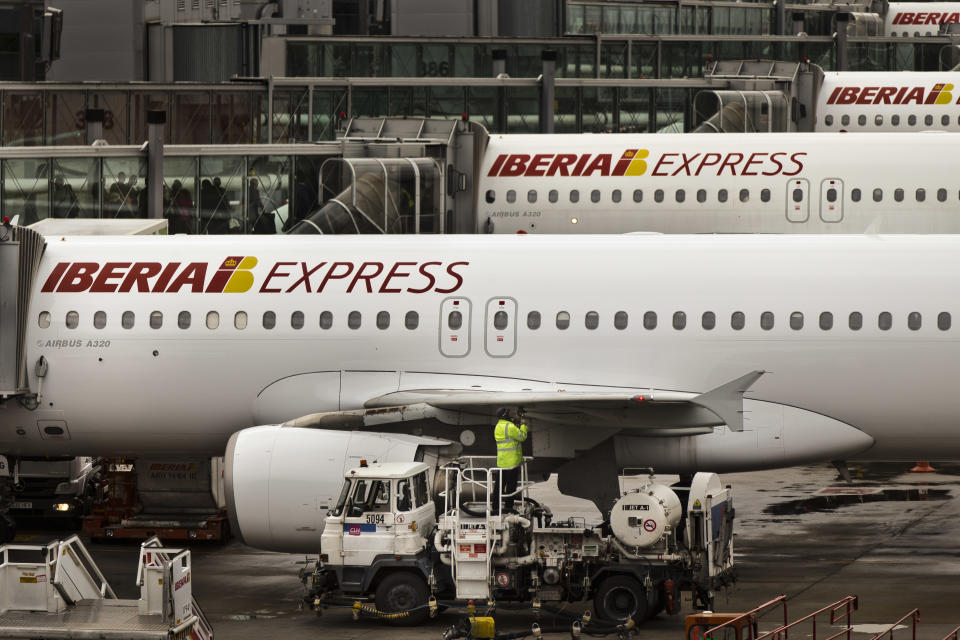 A man works on an Iberia jet while passengers wait to board another plane, in a parking zone at Barajas international airport in Madrid, Friday, Nov. 9, 2012. International Airlines Group on Friday warned that its Spanish carrier Iberia was "in a fight for survival" and unveiled a restructuring plan to cut 4,500 jobs as it reported a drop in third-quarter profit. (AP Photo/Daniel Ochoa de Olza)