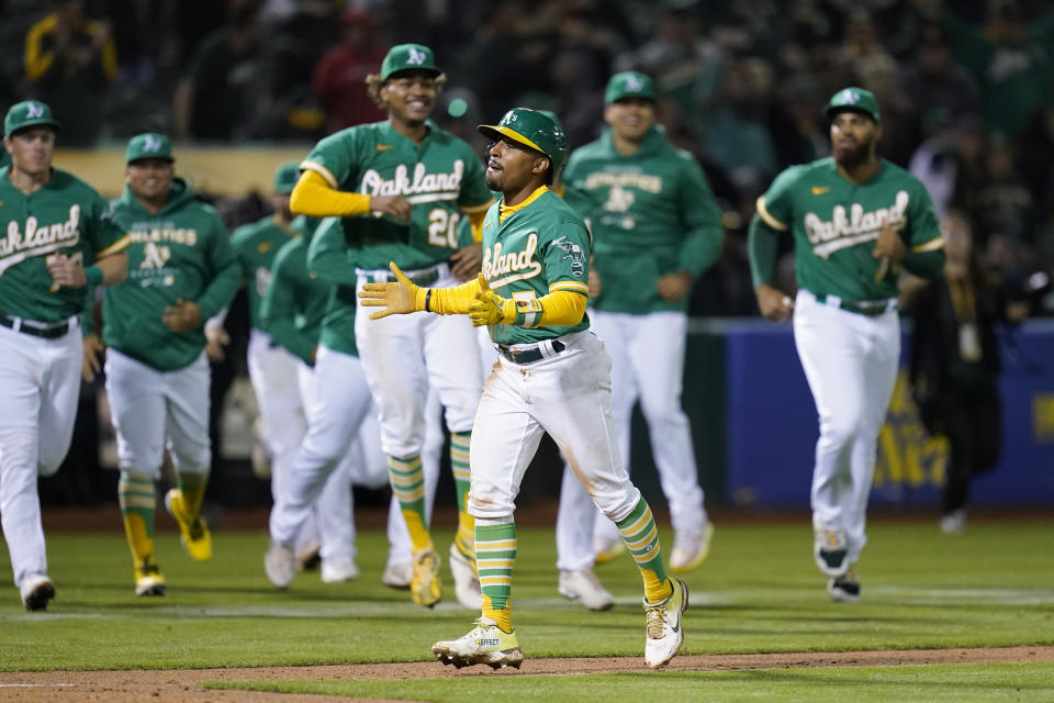 Oakland Athletics' Tony Kemp, center, scores from third on a bases-loaded walk issued to Shea Langeliers by the Los Angeles Angels during the 10th inning of a baseball game in Oakland, Calif., Tuesday, Oct. 4, 2022. The Athletics won 2-1. (AP Photo/Godofredo A. Vásquez)