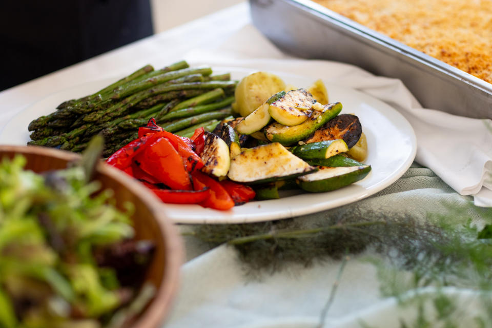 A closeup shows a plate of grilled vegetables on a table.