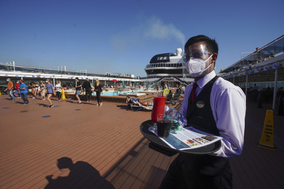 A waiter, wearing Covid-19 protection devices holds a tray of drinks on the MSC Grandiosa cruise ship in Civitavecchia, near Rome, Wednesday, March 31, 2021. MSC Grandiosa, the world's only cruise ship to be operating at the moment, left from Genoa on March 30 and stopped in Civitavecchia near Rome to pick up more passengers and then sail toward Naples, Cagliari, and Malta to be back in Genoa on April 6. For most of the winter, the MSC Grandiosa has been a lonely flag-bearer of the global cruise industry stalled by the pandemic, plying the Mediterranean Sea with seven-night cruises along Italy’s western coast, its major islands and a stop in Malta. (AP Photo/Andrew Medichini)