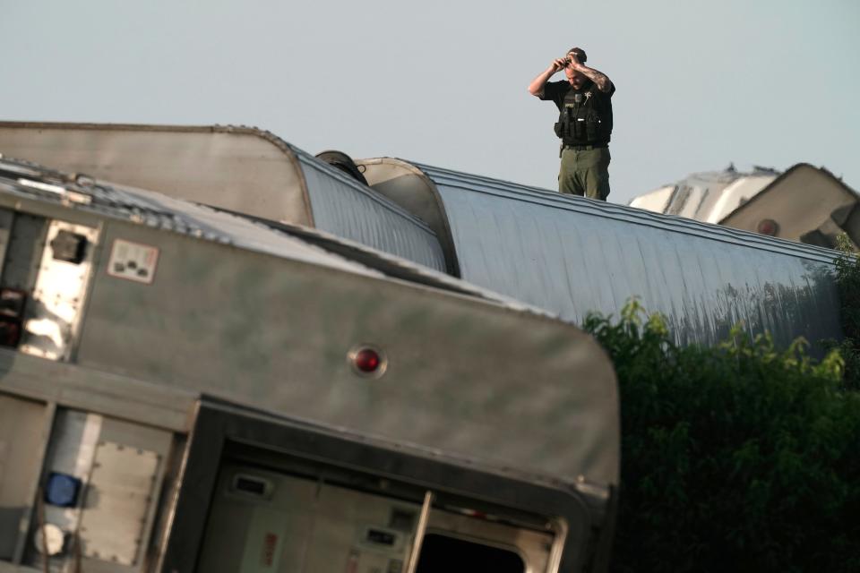 A law enforcement officer inspects the scene of an Amtrak train that derailed after striking a dump truck Monday near Mendon, Mo.