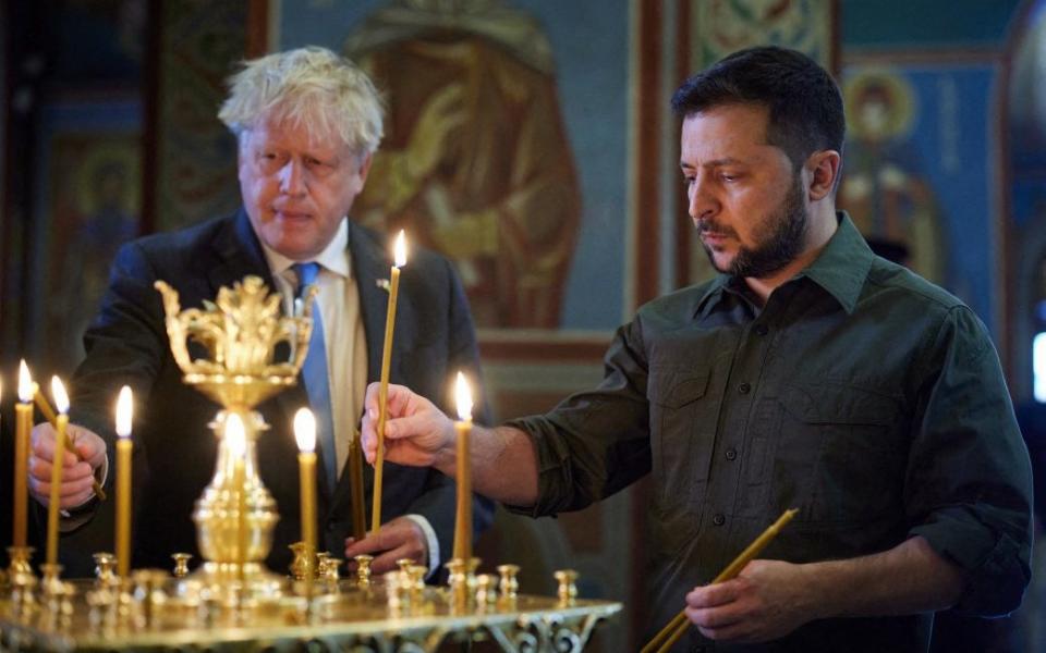 Ukrainian President Volodymyr Zelensky and Prime Minister Boris Johnson light candles at the Cathedral of St Michael of the Golden Domes, in Kyiv, on June 17, 2022. - Ukrainian Presidential Press Service/AFP