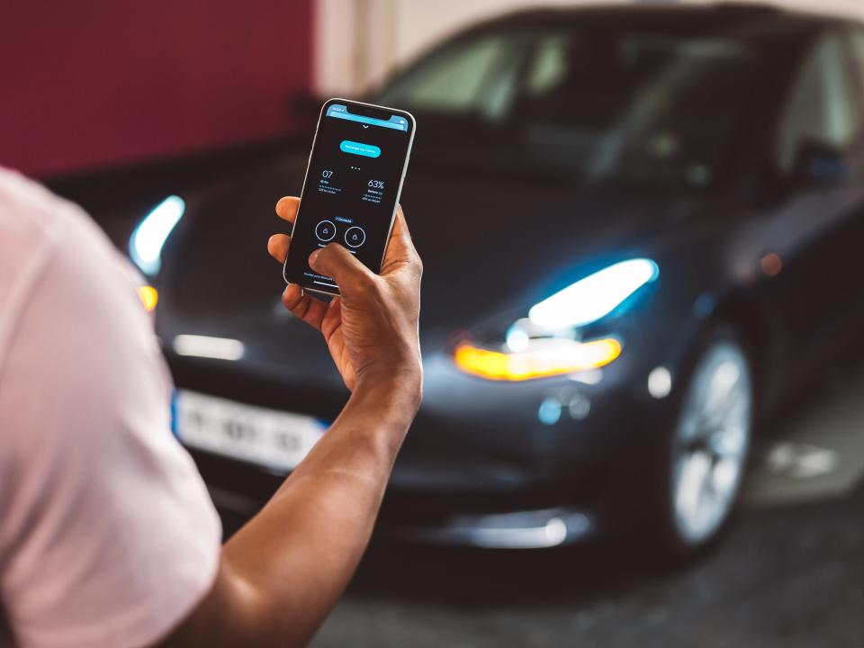 A man is unlocking a Tesla through the Virtuo app on his mobile phone.
