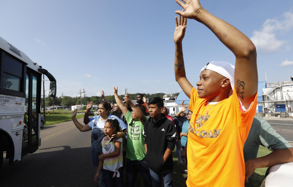 Friends, coworkers and family wave to one of several buses that are filled with detainees, following a U.S. Immigration raid at several Mississippi food processing plants, including this Koch Foods Inc., plant in Morton, Miss., Wednesday, Aug. 7, 2019. The early morning raids were part of a large-scale operation targeting owners as well as undocumented employees. (AP Photo/Rogelio V. Solis)