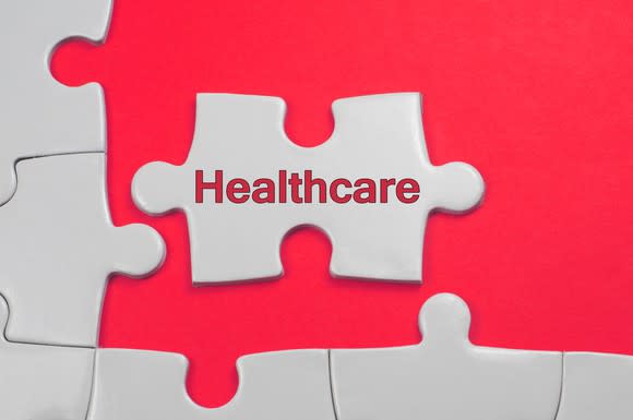 Puzzle pieces being arranged. One piece has the word healthcare written on it.