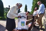 A local resident casts her vote into a mobile ballot box during a parliamentary election in the village of Maidan in Lviv Region