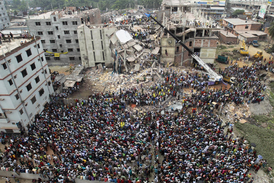 FILE - In this April 25, 2013, file photo, Bangladeshi people gather as rescuers look for survivors and victims at the site of the Rana Plaza building that collapsed a day earlier, in Savar, near Dhaka, Bangladesh. A group set up by European clothing brands that has monitored factory safety in Bangladesh for years plans to leave, with its duties being assumed by a local group including unions and industry figures in the world's second-largest garment manufacturer. The European group and a separate North American group were formed after the collapse in 2013 of Rana Plaza, a building housing five garment factories that made clothing for international brands, that killed at least 1,134 people. The departure, which officials said Thursday, Jan. 16, 2019, was planned for May, follows a protracted tussle with garment manufacturers who wanted Bangladesh's government to form a local watch group to monitor the sector. (AP Photo/A.M.Ahad, File)