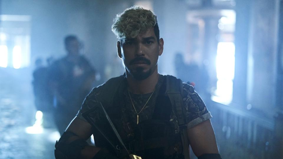 Raúl Castillo as Mikey Guzman looks at the camera and carries a weapon in a still from Army of the Dead.