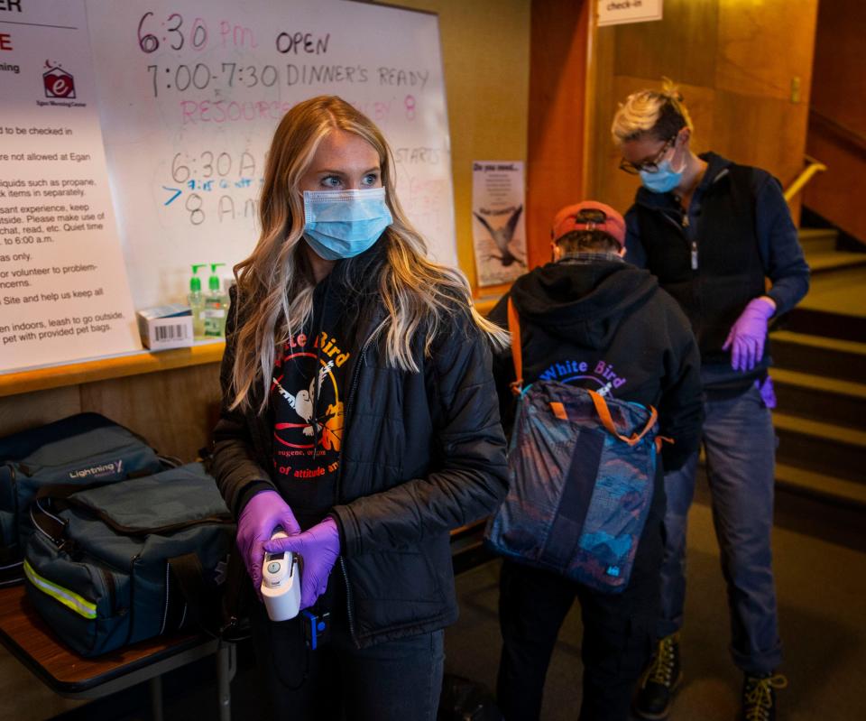 Certified Nursing Assistant Celene Eldrich, left, a volunteer for CAHOOTS waits to screen guests for health concerns at the Egan Warming Center's Springfield, Ore.