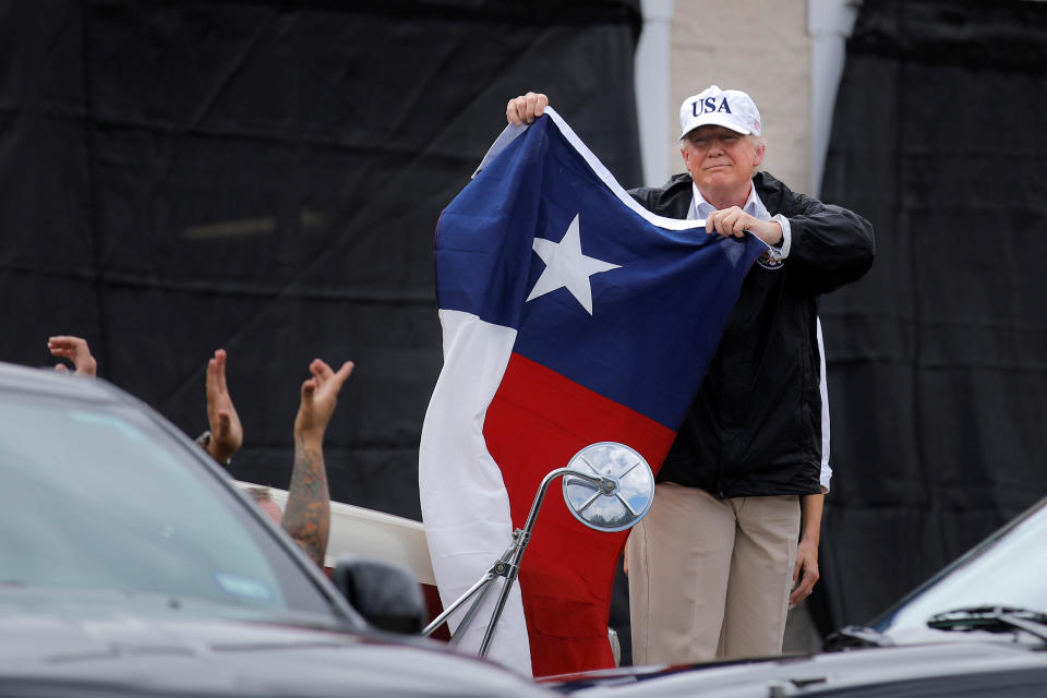 Trump holds a flag of the state of Texas after receiving a briefing on Harvey relief effort in Corpus Christi. (Photo: Carlos Barria / Reuters)