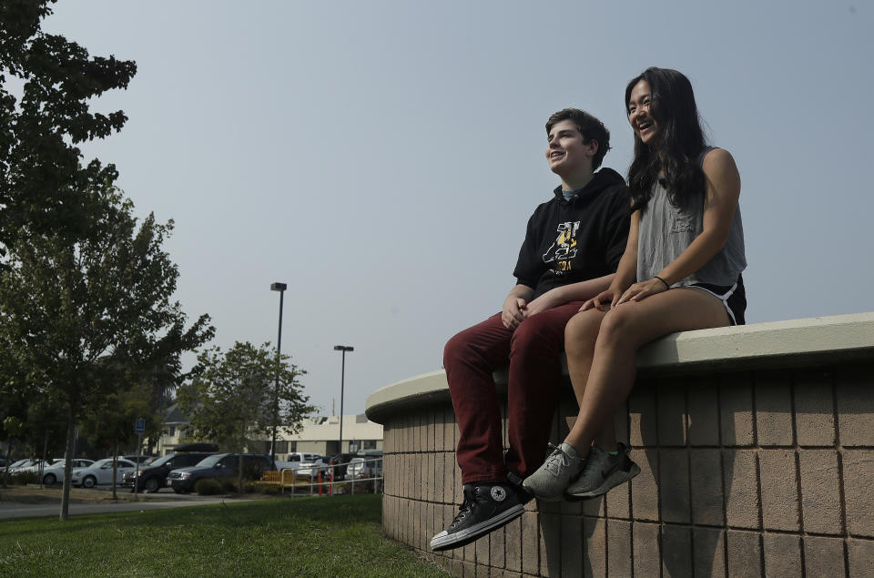 Alameda High School students Henry Mills, left, and Kristen Wong pose for photos on the school's campus in Alameda, Calif., Thursday, Aug. 23, 2018. The relaxed new dress code at public schools in the small city of Alameda, across the bay from San Francisco, is intentionally specific: Midriff-baring shirts are acceptable attire, so are tank tops with spaghetti straps and other once-banned items like micro-mini skirts and short shorts. (AP Photo/Jeff Chiu)