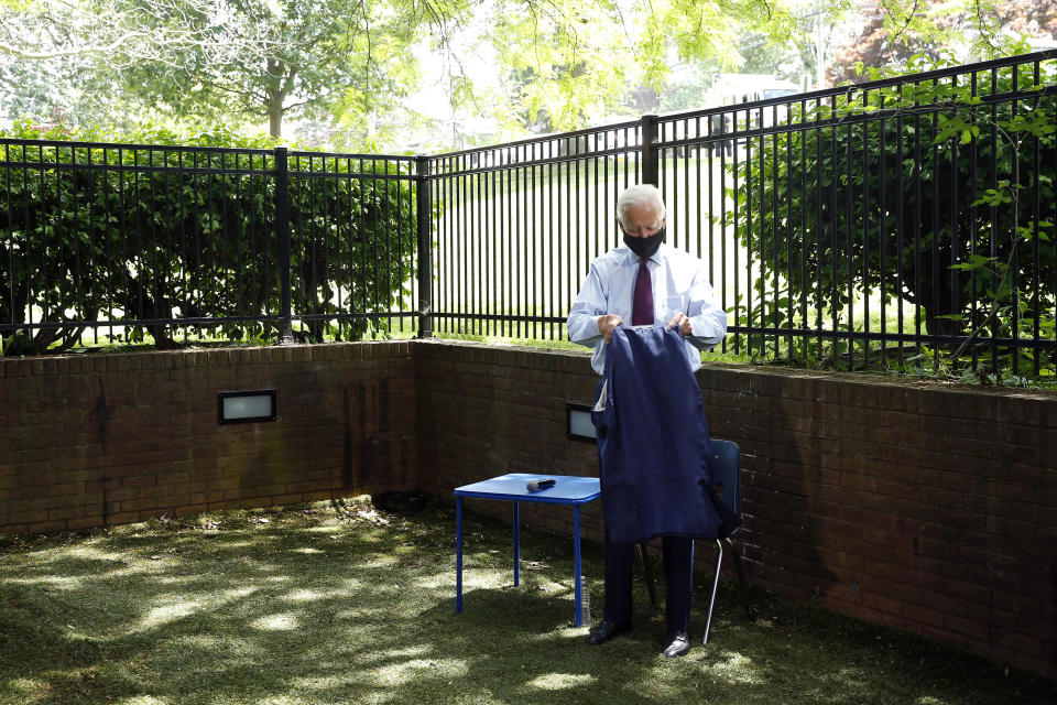 Democratic presidential candidate, former Vice President Joe Biden folds his coat as he arrives to speak with families who have benefited from the Affordable Care Act, Thursday, June 25, 2020, in Lancaster, Pa. (AP Photo/Matt Slocum)