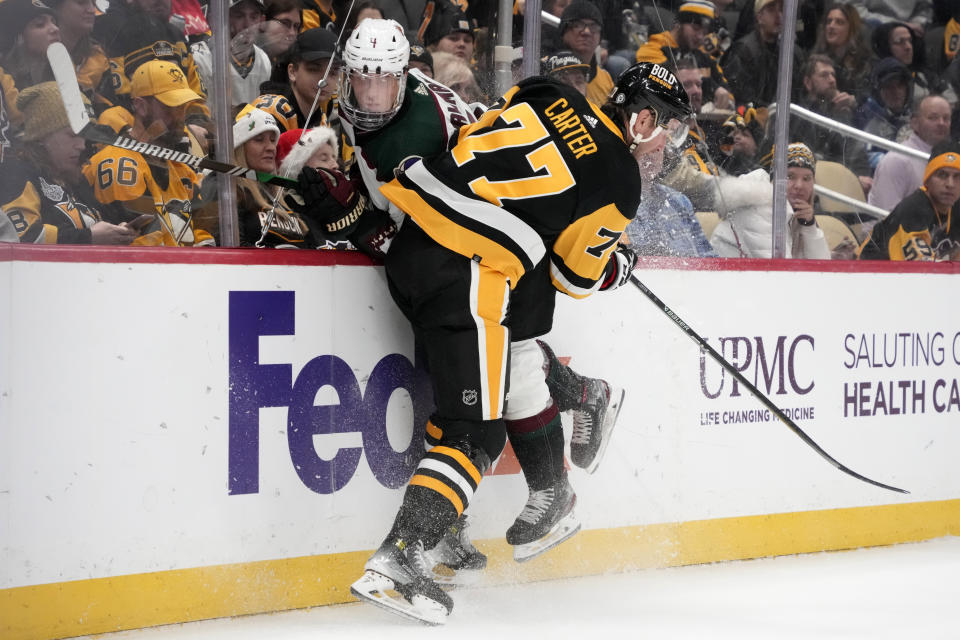 Pittsburgh Penguins' Jeff Carter (77) checks Arizona Coyotes' Juuso Valimaki into the boards during the second period of an NHL hockey game in Pittsburgh, Tuesday, Dec. 12, 2023. (AP Photo/Gene J. Puskar)