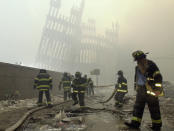 <p>With the skeleton of the World Trade Center twin towers in the background, New York City firefighters work amid debris on Cortlandt Street after the terrorist attacks in this Sept. 11, 2001, photo. (Photo:Mark Lennihan/AP) </p>