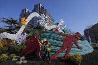 Workers wearing face masks to help protect from the coronavirus set up a decoration for the Winter Olympic Games in Beijing, Sunday, Jan. 16, 2022. Beijing has reported its first local omicron infection, according to state media, weeks before the Winter Olympic Games are due to start. (AP Photo/Andy Wong)