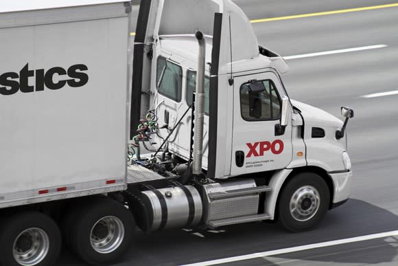 White semi truck on a highway, with XPO logo on side.