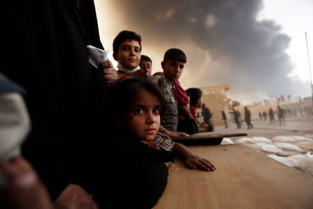 Newly displaced people wait to receive food supplies at a processing center for displaced people In Qayyara, south of Mosul, Iraq October 21, 2016. REUTERS/Zohra Bensemra/Files