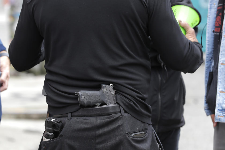 Rick Hearns, part of the volunteer security team at the CHOP (Capitol Hill Occupied Protest) zone, is shown with a handgun in the waistband of his pants, and personal protection spray and a mobile phone in his pockets, Tuesday, June 30, 2020, as he stands outside the Seattle Police Department East Precinct building, which police abandoned earlier in the month after clashes with protesters. (AP Photo/Ted S. Warren)