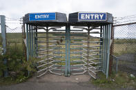 Turnstiles guard the empty site of the former Marchon chemical works, the site of a proposed new coal mine on the outskirts of the Cumbrian town of Whitehaven in northwest England, Monday, Oct. 4, 2021. (AP Photo/Jon Super)