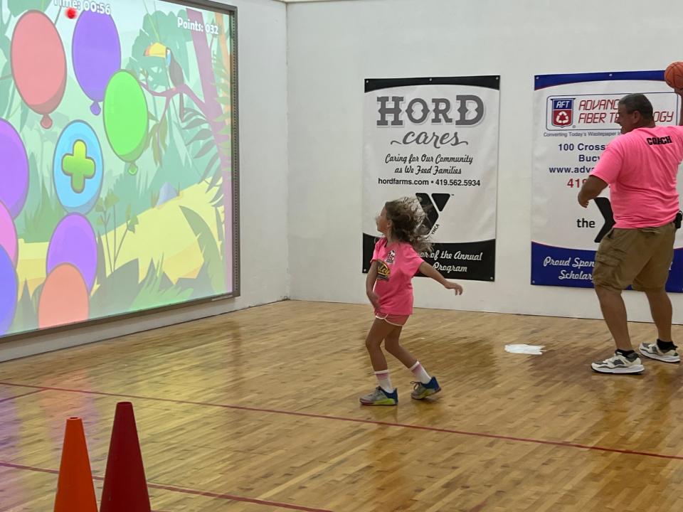 Six-year-old Gracie Brunson and her dad, Darick, check out the interactive ball simulator at the Bucyrus YMCA open house on Saturday.