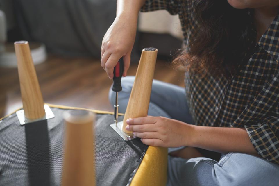 Woman tightens a screw on the underside of a chair.