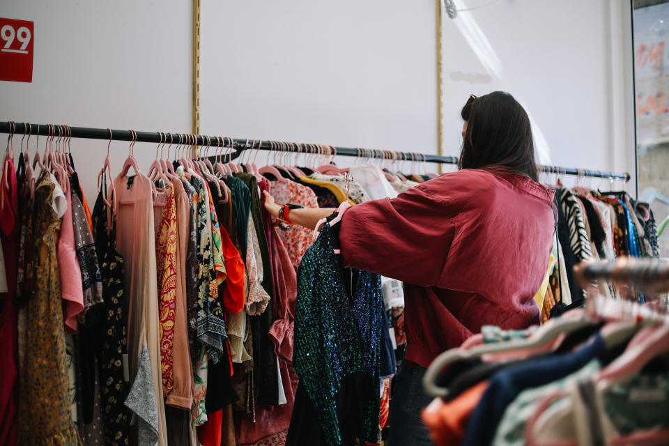 Woman browsing clothes on a rack in a store. Various clothing styles are displayed