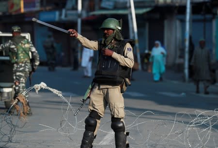 An Indian security personnel stops movement of vehicles at blockade during restrictions after scrapping of the special constitutional status for Kashmir by the Indian government, in Srinagar