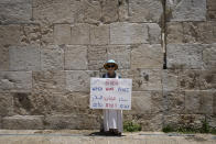 An activist with the Israeli movement Women Wage Peace holds a banner at a rally in front of Jerusalem's walled Old City calling on President Joe Biden to put peace between Israel and the Palestinians on the agenda, in Jerusalem, Thursday, July 14, 2022. Biden is in Israel for a three-day visit, his first as president. He will meet Israeli and Palestinian leaders before continuing on to Saudi Arabia. (AP Photo/Ariel Schalit)