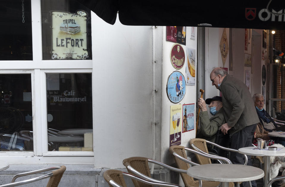 A elderly man is wheeled into a cafe in the historical center of Antwerp, Belgium, Sunday, Oct. 18, 2020. Faced with a resurgence of coronavirus cases, the Belgian government on Friday announced new restrictions to try to hold the disease in check, including a night-time curfew and the closure of cafes, bars and restaurants for a month. The measures will take effect on Monday, Oct. 19, 2020. (AP Photo/Virginia Mayo)