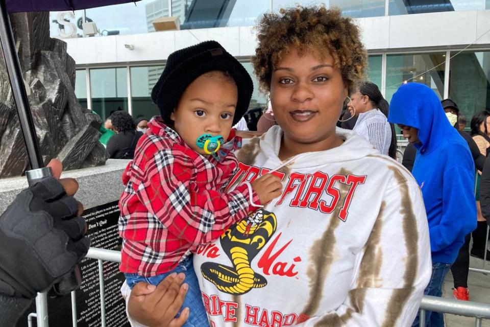 Jenifer Loving, 22, stands in line with her son, Mateo, more than an hour before the doors opened to fans for the memorial service for slain rapper Takeoff, a member of the hip-hop trio Migos, at Atlanta’s State Farm Arena on Friday, Nov. 11, 2022. (AP Photo/Sudhin Thanawala)