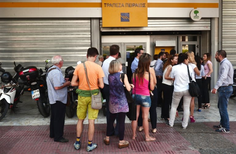 People queue at the ATM machines of the Piraeus bank in central Athens. The country's main banks took a heavy blow, with National Bank and Piraeus falling to the maximum allowed level of minus 30 percent