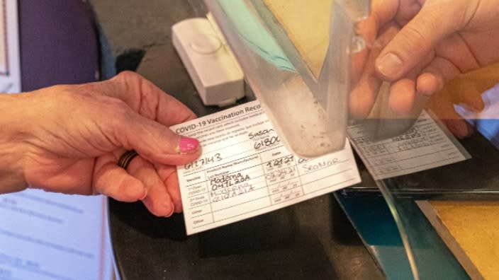 A woman presents an attendant her coronavirus vaccination card to gain entry to Liberty Theatre in Camas, Washington. (Photo by Nathan Howard/Getty Images)