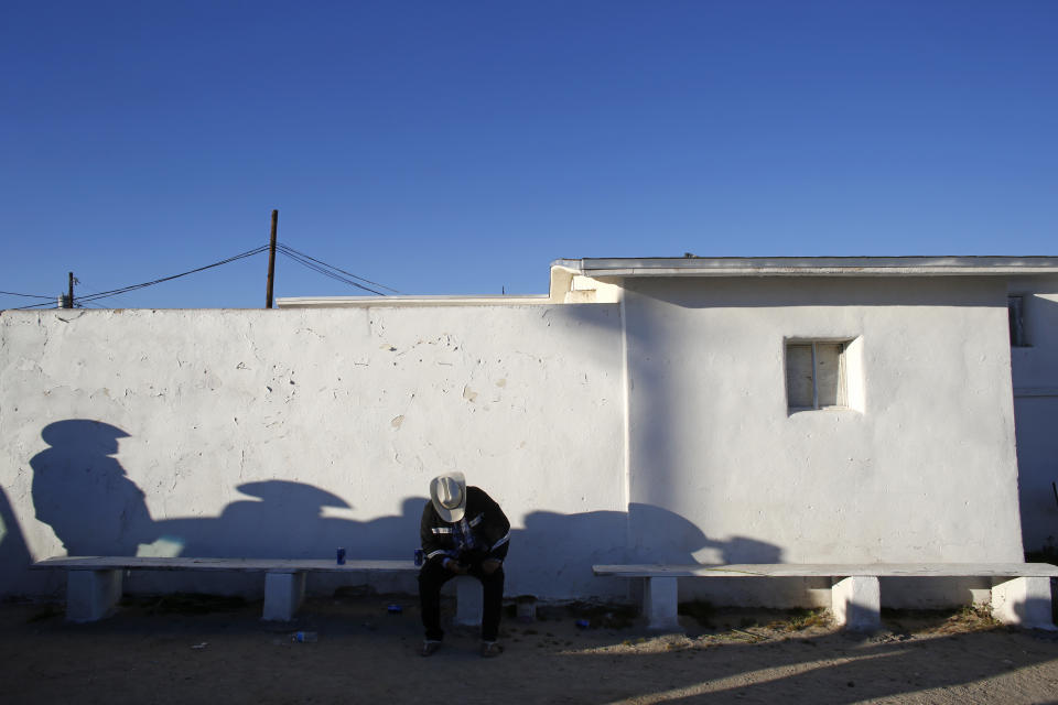 In this Feb. 8, 2020, photo, men gather outside of the Our Lady of Guadalupe church in the town of Guadalupe, Ariz., near Phoenix. Founded by Yaqui Indian refugees from south of the border more than a century ago, the town named for Mexico's patron saint, is proud of its history but wary of outsiders as it prepares for the 2020 Census count its leaders hope will help better fund a $12 million budget to fill potholes and mend aging sewage lines. (AP Photo/Dario Lopez-MIlls)