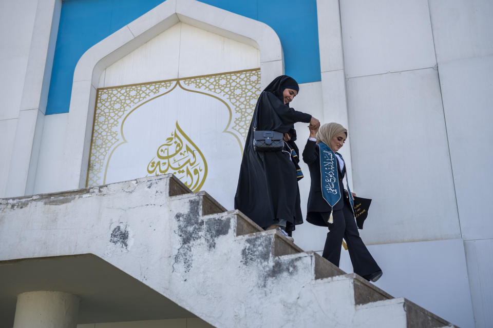 Two students celebrate their graduation at the upscale Qalaat Baghdad restaurant complex built in a former palace of Saddam Hussein along the Tigris River in Baghdad, Iraq, Tuesday, Feb. 28, 2023. (AP Photo/Jerome Delay)