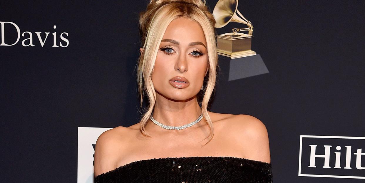 paris hilton, a young woman wearing a black sequin off shoulder dress, looking at the camera, blonde hair pinned up on head