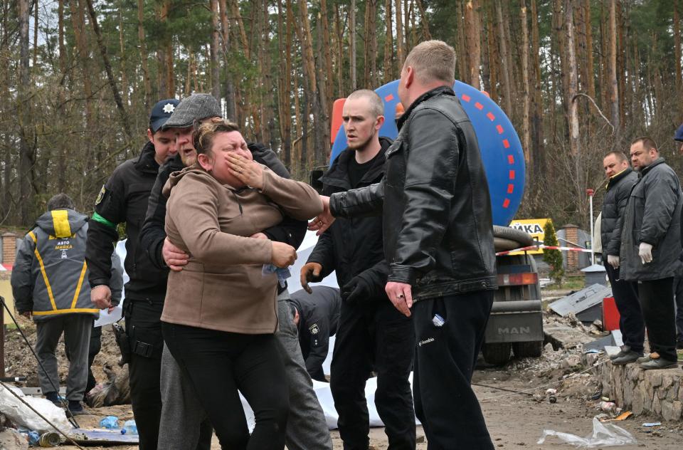 TOPSHOT - A Ukrainian mother reacts after the body of her son was discovered in a manhole at a petrol station in the outskirts of the Buzova village, west of Kyiv, on April 10, 2022. - At least two bodies, appearing to be clad in a mix of civilian and military clothing, were discovered in a manhole at the back of a destroyed motorway petrol station. (Photo by Sergei SUPINSKY / AFP) (Photo by SERGEI SUPINSKY/AFP via Getty Images)