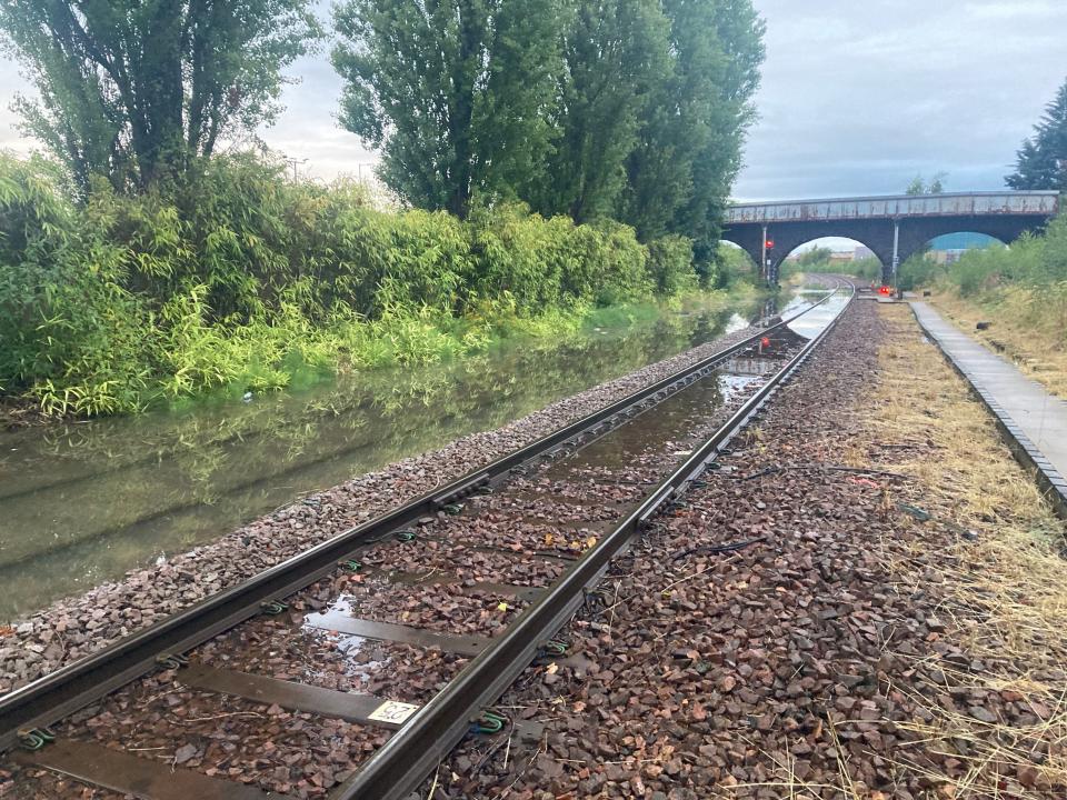 Rail line submerged by flooding at Perth station (left) (PA)