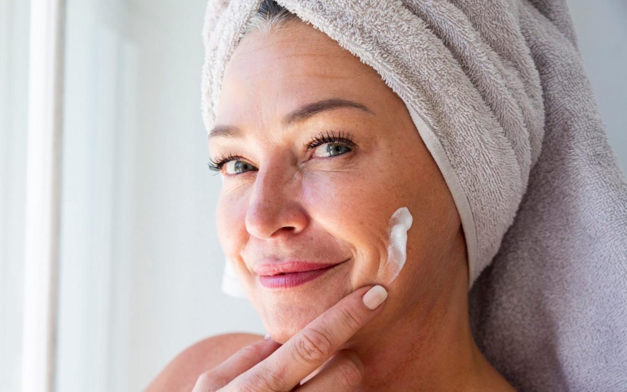 Smiling woman putting on face cream