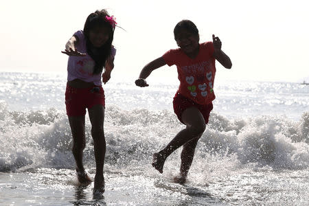 FILE PHOTO: Children run away from a wave during their first visit to the sea, during a special program organised by the Ministry of Education at Agua Dulce Beach in Lima, Peru, September 30, 2017. REUTERS/Guadalupe Pardo