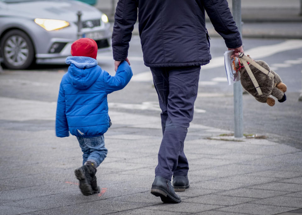 A man and his son walk in downtown Frankfurt, Germany, Tuesday, Jan. 19, 2021. German politics decides about further Coronavirus restrictions on Tuesday. (AP Photo/Michael Probst)