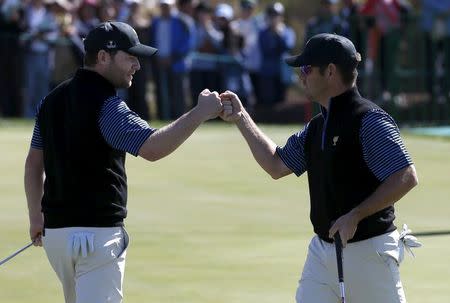 International team members Louis Oosthuizen (L) and Branden Grace of South Africa celebrate their point against U.S. team members Jordan Spieth and Dustin Johnson on the 14th hole during the four ball matches of the 2015 Presidents Cup golf tournament at the Jack Nicklaus Golf Club in Incheon, South Korea, October 9, 2015. REUTERS/Toru Hanai