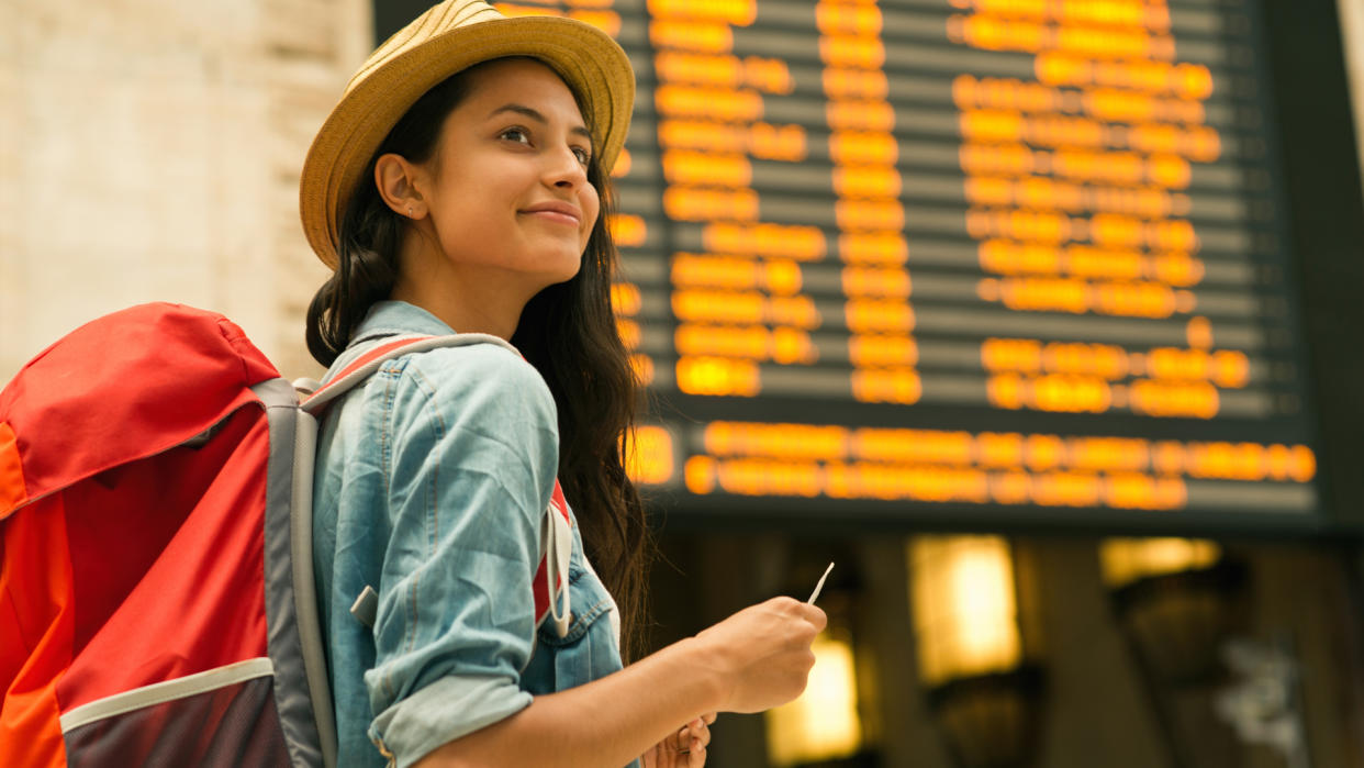 Young woman checking her train in time board.